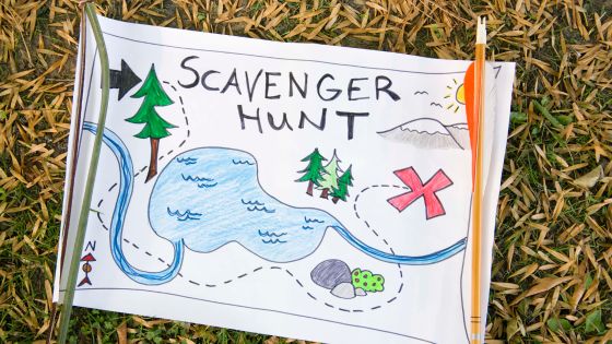 a picture of a hand-drawn play map with a tree, lake, rocks, mountains, and x marking the spot for treasure. The drawing has been made for a scavenger hunt, which is written in large capital letters on the top of the picture.