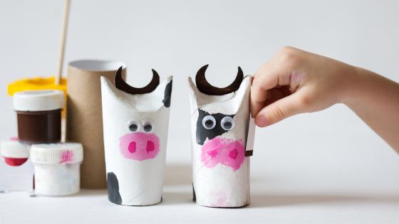 Recycled craft made from empty cardboard tubes / toilet rolls. They have been painted black, white, and pink with googly eyes added to make cows.