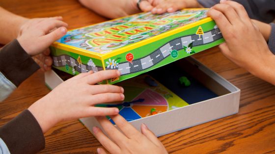 A family are opening a board game box together with what appears to be a colourful spinner inside.