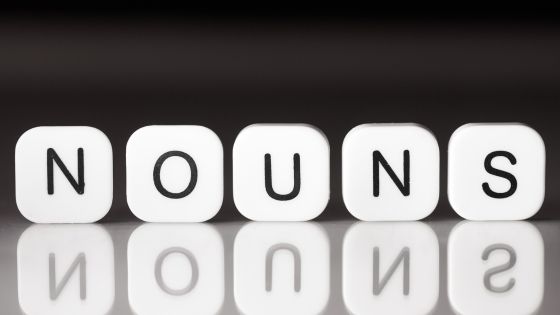Image shows five letter blocks on a table that spell "nouns".