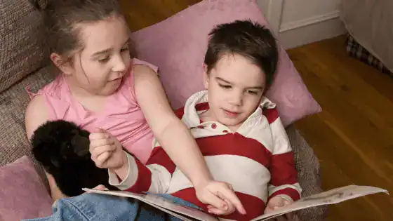 A boy and a girl looking at a book together.