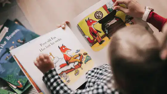 A child reading a book that is open about a fox.