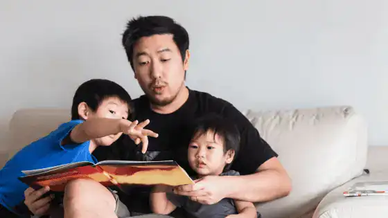 Father reading a story to his two children sat on the sofa.