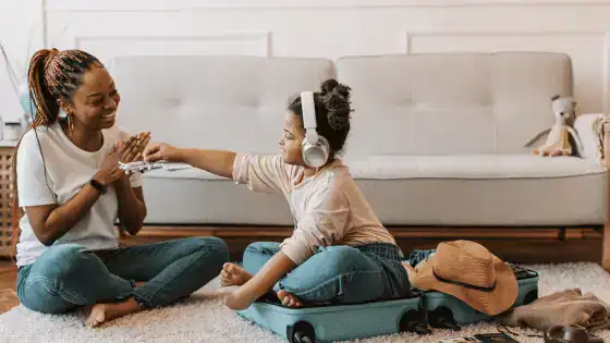 Mother and daughter role playing holidays with a suitcase and toy aeroplane.
