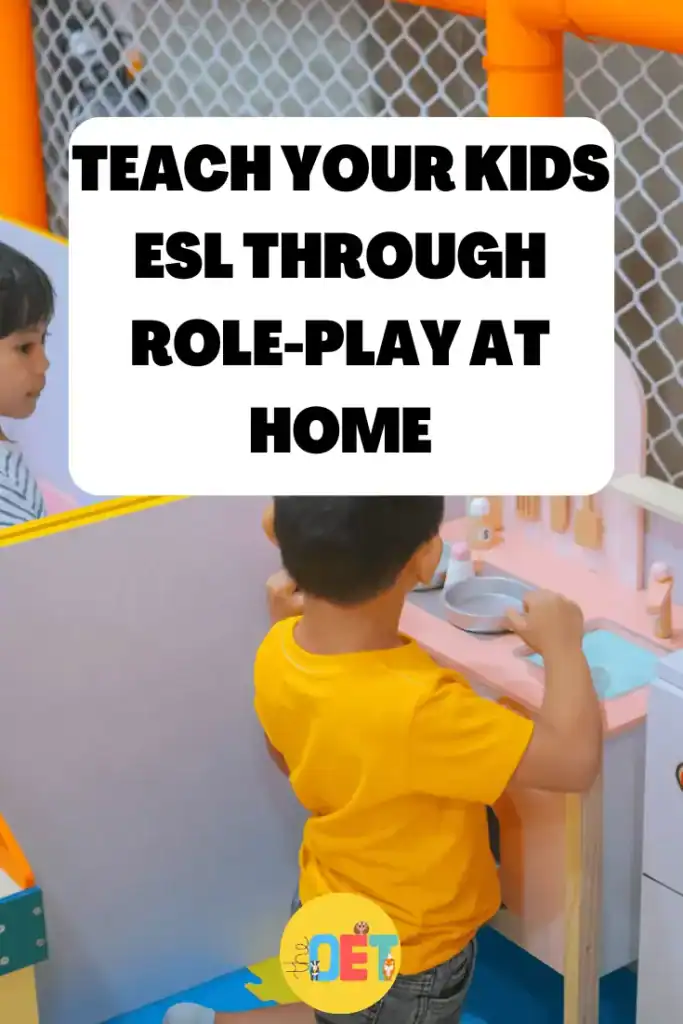 Two young children are in an indoor play area role playing cooking in a play kitchen. Text reads "teach your kids esl through role play at home".