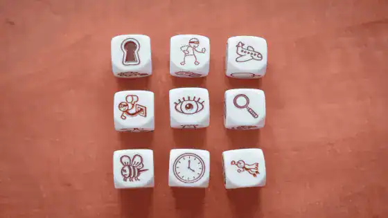 9 dice are on the table, each face on the dice has a different picture to create a story