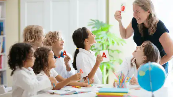 Teacher is holding a phonics card up and students are looking at her and holding up the same phonics card.
