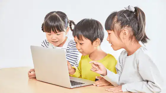 Three children are looking at a laptop together