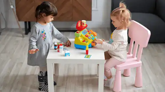 Two young girls playing together by role playing shop keepers