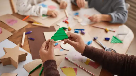Children sat at the table creating xmas paper crafts.