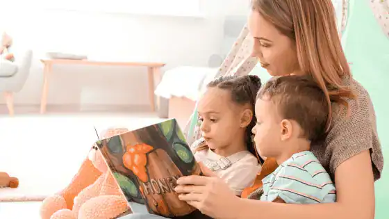 A mother reading a children' book with her 2 children.