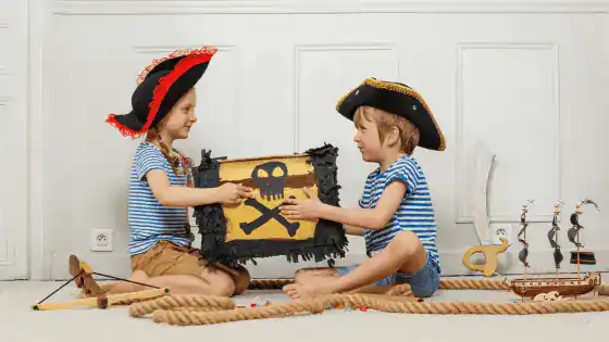 Two children dressed in pretend role play as pirates with a pirate treasure chest