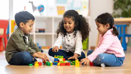 three children sat on the floor playing together image